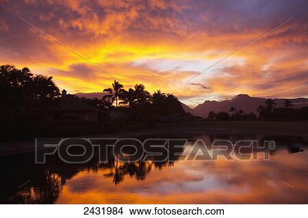Picture - Sunset over the West Maui Mountains with palm trees reflecting in pond at Maui Country Club; Spreckelsville, Maui, Hawaii, United States of America. Fotosearch
