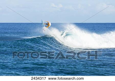 Stock Photo - Surfer riding perfect waves in the South Pacific; Tahiti, French Polynesia. Fotosearch