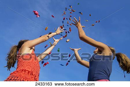 Stock Image - Teenage girls throw sweets in air; United Kingdom. Fotosearch
