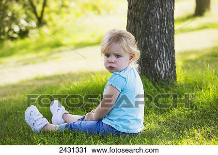 Toddler girl sitting in a park beside a tree with a thoughtful expression on her face; Edmonton, Alberta, Canada View Large Photo Image Stock Image - Toddler girl sitting in a park beside a tree with a thoughtful expression on her face; Edmonton, Alberta, Canada. Fotosearch