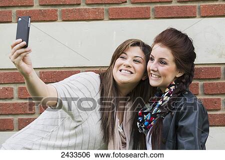 Stock Photograph - Two friends doing self-portrait to the camera; Edmonton, Alberta, Canada. Fotosearch