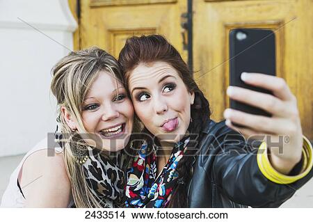 Two friends taking a self-portrait with a cell phone; Edmonton, Alberta, Canada View Large Photo Image Picture - Two friends taking a self-portrait with a cell phone; Edmonton, Alberta, Canada. Fotosearch