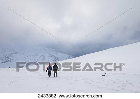Stock Image - Two people walking in snow covered, winter conditions on Beinn an Dothaidh, near Bridge of Orchy; Argyll and Bute, Scotland. Fotosearch