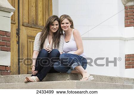 Stock Photo - Two sisters sitting on school steps; Edmonton, Alberta, Canada. Fotosearch