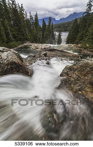 Water flows over lower Myra Falls in Strathcona Provincial Park, with Buttle lake seen in the distance; British Columbia, Canada View Large Photo Image Stock Photograph - Water flows over lower Myra Falls in Strathcona Provincial Park, with Buttle lake seen in the distance; British Columbia, Canada. Fotosearch