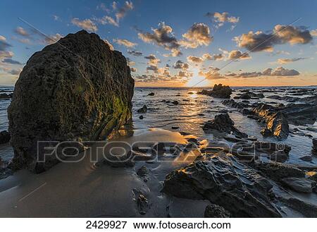 Stock Photo - Water washes over the rocks and sand on the shore at sunset; Bolonia, Cadiz, Andalusia, Spain. Fotosearch