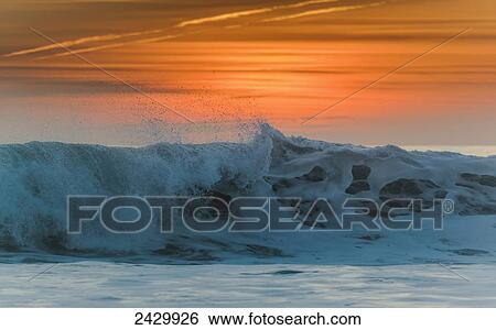 Waves breaking at the shore with a glowing orange sky at sunset; Tarifa, Cadiz, Andalusia, Spain View Large Photo Image Stock Photograph - Waves breaking at the shore with a glowing orange sky at sunset; Tarifa, Cadiz, Andalusia, Spain. Fotosearch