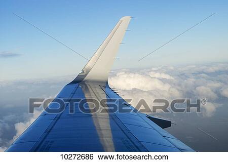 Stock Photograph - Wing of an airplane in a blue sky with cloud; Patagonia, Chile. Fotosearch