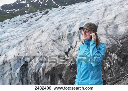 Woman talking on a cell phone in front of Shoup glacier, Shoup Bay State Marine Park, Prince William Sound; Valdez, Alaska, United States of America View Large Photo Image Stock Photo - Woman talking on a cell phone in front of Shoup glacier, Shoup Bay State Marine Park, Prince William Sound; Valdez, Alaska, United States of America. Fotosearch