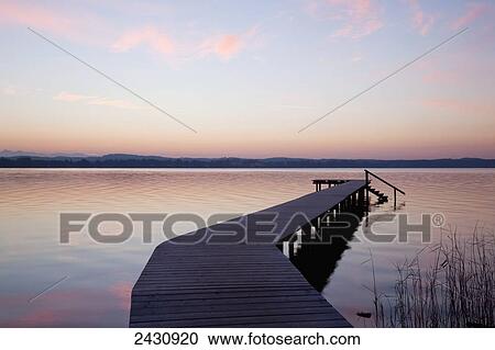 Wooden dock leading out to the water at sunset; Starnberger See, Bavaria, Germany View Large Photo Image Stock Image - Wooden dock leading out to the water at sunset; Starnberger See, Bavaria, Germany. Fotosearch