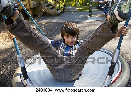 Young boy playing on dish swing at a playground in autumn; Langley, British Columbia, Canada View Large Photo Image Picture - Young boy playing on dish swing at a playground in autumn; Langley, British Columbia, Canada. Fotosearch