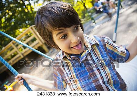 Young boy playing on dish swing at a playground in a park in autumn; Langley, British Columbia, Canada View Large Photo Image Stock Photo - Young boy playing on dish swing at a playground in a park in autumn; Langley, British Columbia, Canada. Fotosearch