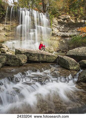 Picture - Young boy sitting on a rock watching the falls at Rock Glen Conservation Area; Ontario, Canada. Fotosearch