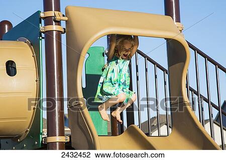 Young girl hanging on top of a slide in a playground; Spruce Grove, Alberta, Canada View Large Photo Image Stock Image - Young girl hanging on top of a slide in a playground; Spruce Grove, Alberta, Canada. Fotosearch