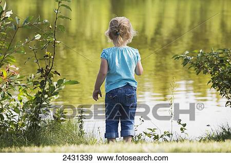Young girl looking at water from the shore of a lake in a park; Edmonton, Alberta, Canada View Large Photo Image Stock Photo - Young girl looking at water from the shore of a lake in a park; Edmonton, Alberta, Canada. Fotosearch