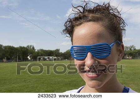 Stock Image - Young woman with funny eyeglasses in the park; Edmonton, Alberta, Canada. Fotosearch