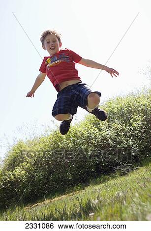 Stock Photograph - 10-Year-Old Boy Jumping In Mid-Air Outdoors; Langley British Columbia Canada. Fotosearch