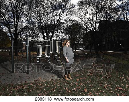 Stock Photo - 37-year-old pregnant woman standing in front of a jungle gym in a public park; Montreal, Quebec, Canada. Fotosearch