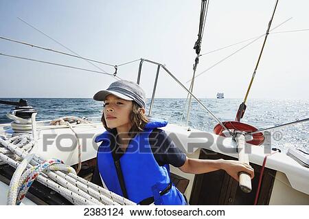 Picture - A 7-year-old mixed race boy piloting a sailboat on Lake Ontario; Toronto, Ontario, Canada. Fotosearch