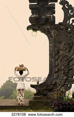 A balinese woman carrying a basket for religious offering on her head; Bali, Indonesia View Large Photo Image Stock Photo - A balinese woman carrying a basket for religious offering on her head; Bali, Indonesia. Fotosearch