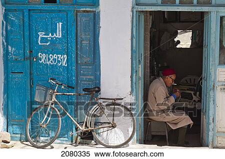 Stock Photography - A Barber Sits In His Shop Doorway; Kairouan, Tunisia, North Africa. Fotosearch
