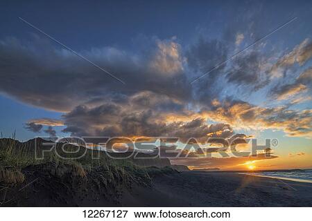 Stock Photo - A beautiful sunrise occurs over the beach and town of Vik along the south coast of Iceland; Vik, Iceland. Fotosearch