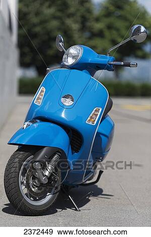 Stock Photo - A Blue Motor Scooter Parked On The Side Of A Street; Locarno, Ticino, Switzerland. Fotosearch