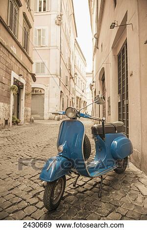 Stock Photo - A blue motor scooter parked outside a residential building; Rome, Lazio, Italy. Fotosearch