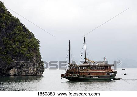 Stock Image - A Boat Going Past A Large Cliff. Fotosearch