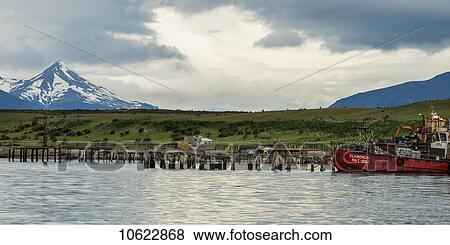 Stock Photo - A boat in the water with a mountain peak in the distance; Patagonia, Chile. Fotosearch