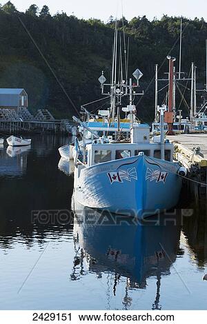 Stock Image - A boat moored along a dock in a harbour, Gros Morne National Park; Trout River, Newfoundland, Canada. Fotosearch
