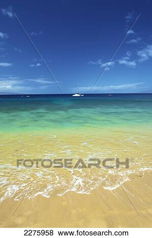Stock Photo - A boat mooring in the water in the distance as viewed from the beach on the coast of an hawaiian island; Hawaii, United States of America. Fotosearch
