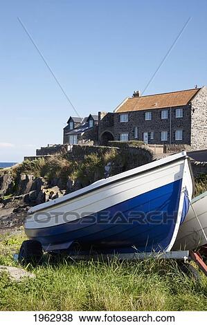 A Boat On The Shore With Buildings In The Background; Craster, Northumberland, England View Large Photo Image Stock Photo - A Boat On The Shore With Buildings In The Background; Craster, Northumberland, England. Fotosearch