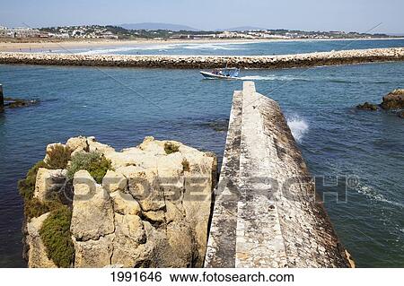 Stock Photograph - A Boat Travelling Along The Coast; Lagos Algarve Portugal. Fotosearch