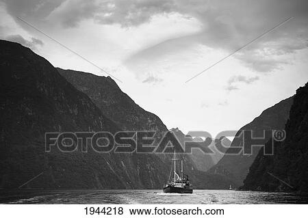 A Boat Travels Through A Waterway Between The Mountains; Milford Sound South Island New Zealand View Large Photo Image Stock Photo - A Boat Travels Through A Waterway Between The Mountains; Milford Sound South Island New Zealand. Fotosearch