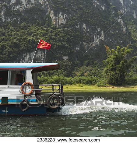 Stock Photo - A Boat With A Chinese Flag Traveling Down Li River; Guilin, Guangxi, China. Fotosearch