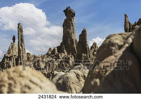 Picture - A Bolivian flute player stands on the mounds of mud in the Valley of the Moon; La Paz, Bolivia. Fotosearch