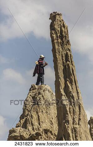 Stock Image - A Bolivian flute player stands on the mounds of mud in the Valley of the Moon; La Paz, Bolivia. Fotosearch