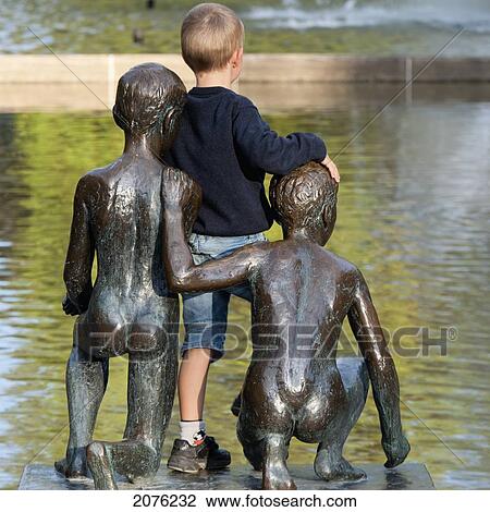 A Boy Stands Leaning On A Statue Of Boys Along The Water In Spikersuppa Park; Oslo Norway View Large Photo Image Stock Image - A Boy Stands Leaning On A Statue Of Boys Along The Water In Spikersuppa Park; Oslo Norway. Fotosearch