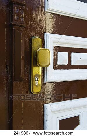Stock Photo - A brass doorknob with lock on a painted brown and white wooden door; Hamburg, Germany. Fotosearch