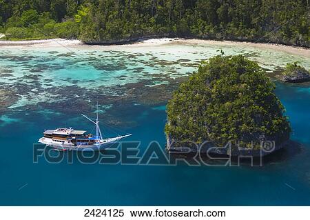 Stock Photography - A Bugis schooner, live-aboard dive vessel, at anchor in a limestone island lagoon; Uranie Island, Raja Ampat, West Papua, Indonesia. Fotosearch