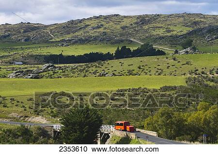Stock Image - A Bus Drives Down A Scenic Stretch Of Road Just Outside Of Hyde In New Zealand's Otago Region; New Zealand. Fotosearch