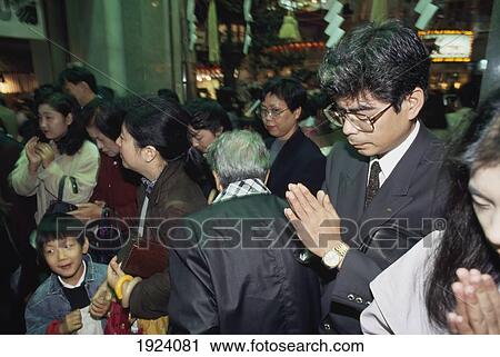 Stock Image - A Business Man Prays At Ebisku Shrine. Fotosearch