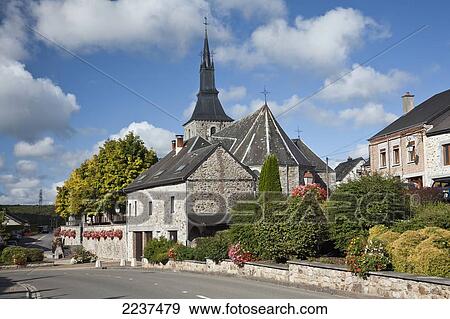 Stock Photo - A Church And Hanging Flower Baskets On A Stone Wall Along A Street; Hergnies Ardennes France. Fotosearch