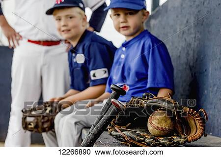A closeup focus on a game used baseball and glove with young boy players in uniform sitting on the dugout bench in the background; Fort McMurray, Alberta, Canada View Large Photo Image Stock Image - A closeup focus on a game used baseball and glove with young boy players in uniform sitting on the dugout bench in the background; Fort McMurray, Alberta, Canada. Fotosearch