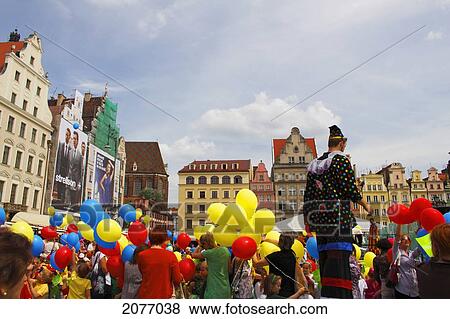 A Clown On Stilts Amongst A Crowd Holding Colourful Balloons During A Parade On Rynek Square Or Market Square; Wroclaw Poland View Large Photo Image Stock Photo - A Clown On Stilts Amongst A Crowd Holding Colourful Balloons During A Parade On Rynek Square Or Market Square; Wroclaw Poland. Fotosearch