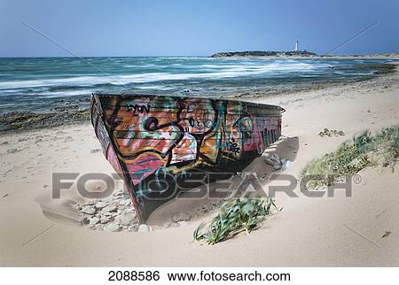 Stock Photograph - A Colourfully Painted Rowboat On Canos De Meca Beach; Cape Trafalgar Cadiz Andalusia Spain. Fotosearch