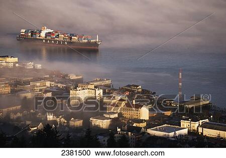 Stock Image - A container ship emerges from the fog; Astoria, Oregon, United States of America. Fotosearch