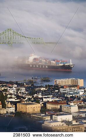 Stock Image - A container ship emerges from the fog; Astoria, Oregon, United States of America. Fotosearch