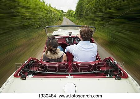 A couple drives down a narrow road in a convertible car; East Sussex, England View Large Photo Image Picture - A couple drives down a narrow road in a convertible car; East Sussex, England. Fotosearch